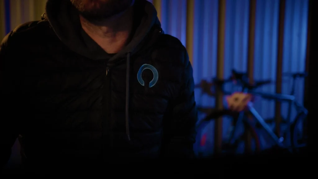 Close-up of a technician wearing a Drotek branded jacket, working in a dimly lit indoor environment.